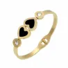 Pulsera dorada fina con dos pequeños corazones y un círculo con números romanos y un cristal en el centro.