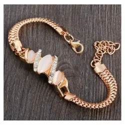Pulsera dorada con una piedra brillante en el centro y pequeños destellos a los lados.