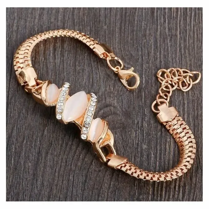 Pulsera dorada con una piedra brillante en el centro y pequeños destellos a los lados.