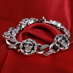 Pulsera plateada de eslabones con calaveras talladas en acero envejecido.