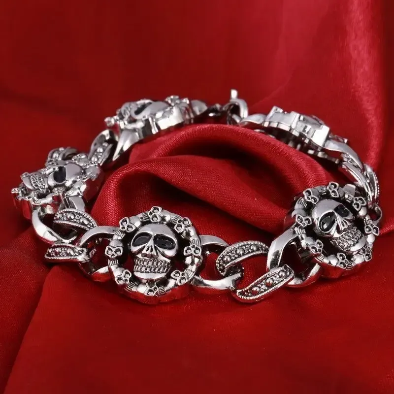 Pulsera plateada de eslabones con calaveras talladas en acero envejecido.