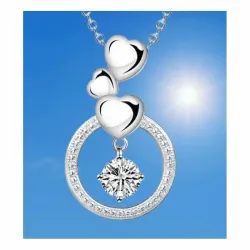 Colgante de plata con forma de círculo que contiene tres corazones y un pequeño destello central.
