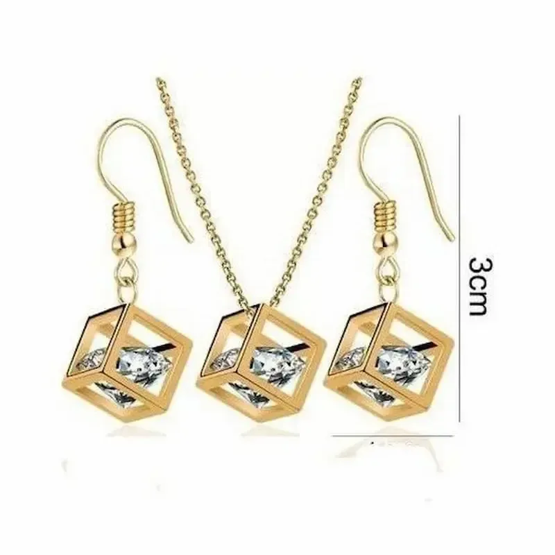 Conjunto de collar y pendientes dorados con cubos y piedra de cristal blanco en el centro.