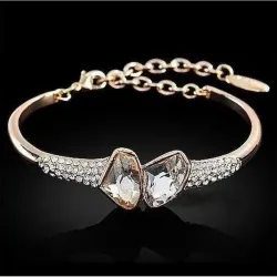 Pulsera de bisutería en metal dorado con piedras blancas, mostrando su brillo y engastes sobre la muñeca.