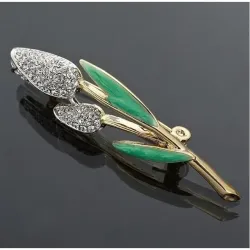 Broche de bisutería vintage con hojas verdes esmaltadas y cristales blancos, mostrando su detalle y brillo sobre una prenda.