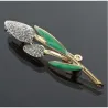 Broche de bisutería vintage con hojas verdes esmaltadas y cristales blancos, mostrando su detalle y brillo sobre una prenda.