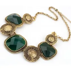 Collar de bisutería vintage en acero dorado con piedras verdes, mostrando su diseño barroco y brillo facetado.