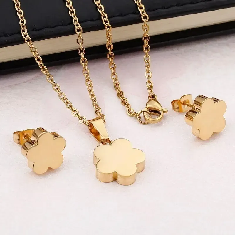 Set collar y pendientes bisutería mujer con trébol de cuatro hojas acabado oro 18k sobre fondo blanco.