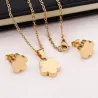 Set collar y pendientes bisutería mujer con trébol de cuatro hojas acabado oro 18k sobre fondo blanco.