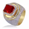 Anillo bisutería hombre chapado oro blanco con cristales rojos centrales y blancos alrededor, fondo neutro.
