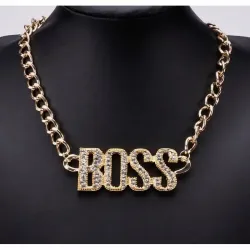 Collar bisutería hombre estilo hip hop con colgante grande dorado y cristales, sobre fondo oscuro.