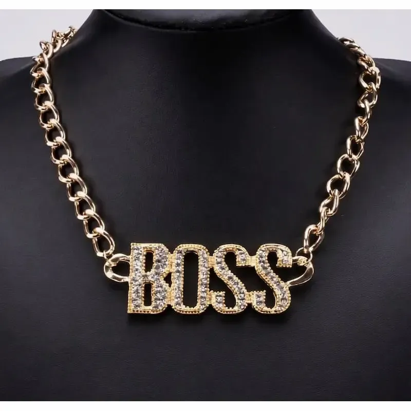 Collar bisutería hombre estilo hip hop con colgante grande dorado y cristales, sobre fondo oscuro.