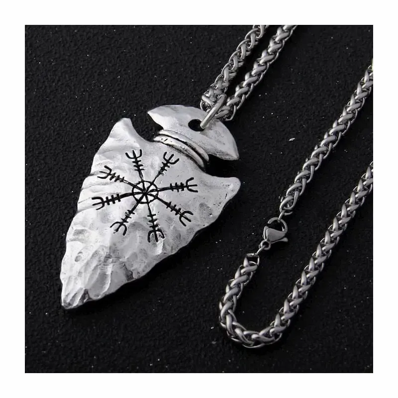 Collar bisutería hombre con colgante punta de lanza y runa vikinga en acero, sobre fondo oscuro texturizado.