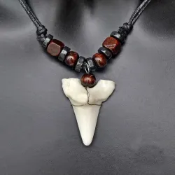 Colgante con forma de diente de tiburón en tono marfil, cordón ajustable y acabado natural.