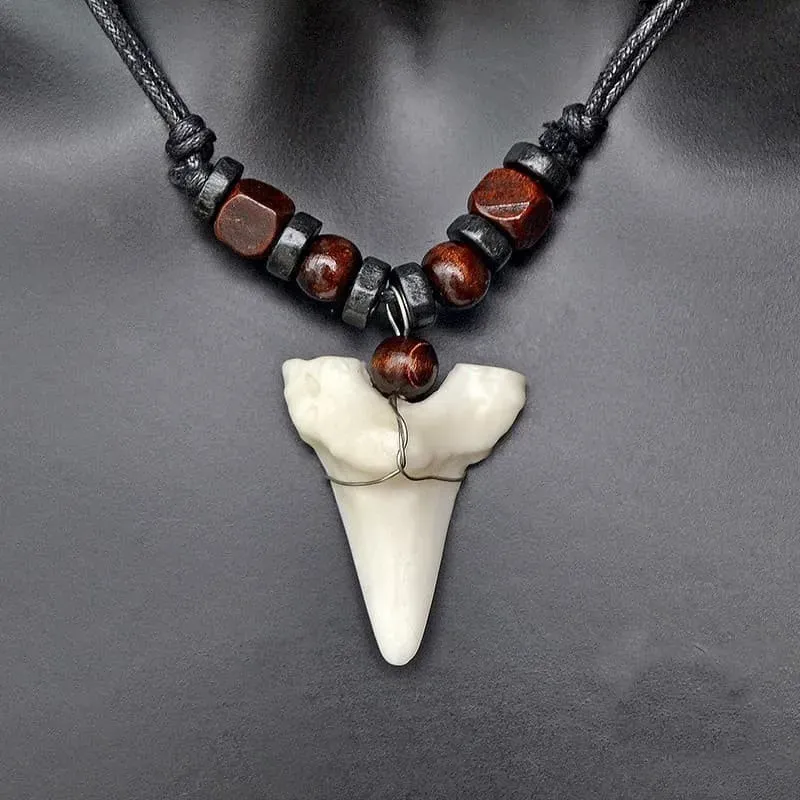 Colgante con forma de diente de tiburón en tono marfil, cordón ajustable y acabado natural.