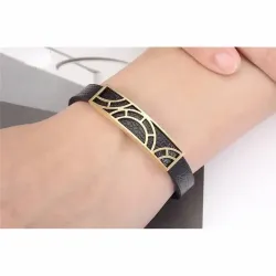 Pulsera de acero con inserciones de piel negra y detalles dorados, cierre de presión y acabado brillante.