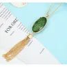 Colgante con piedra verde y borla colgando de una cadena dorada.