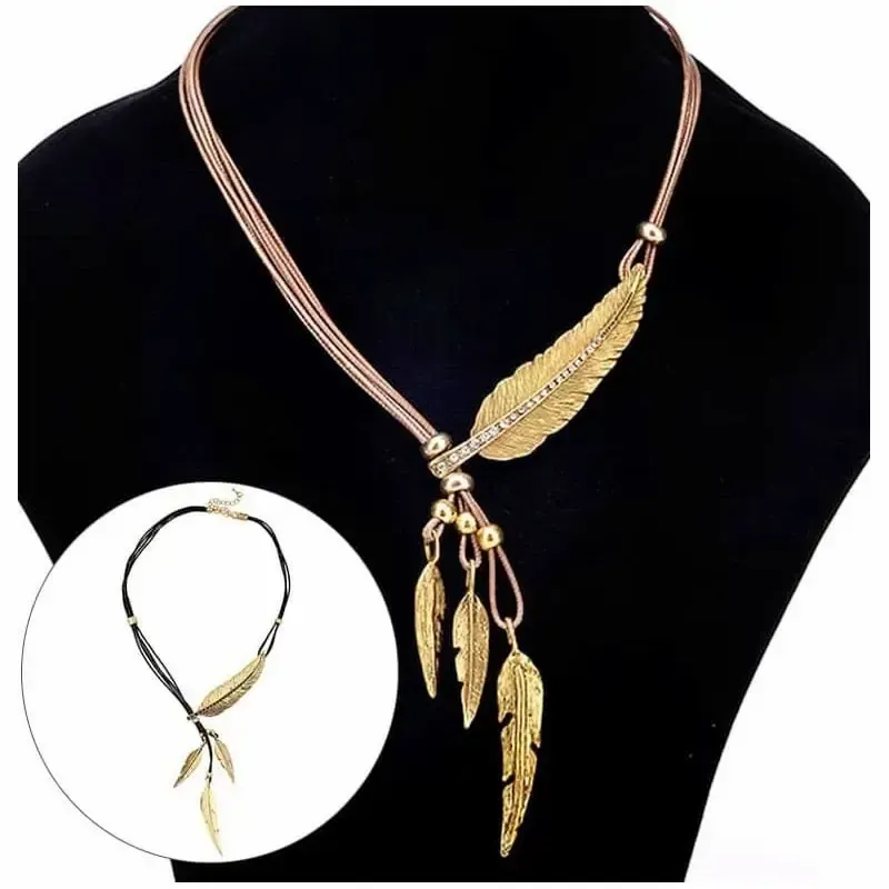 Colgante dorado con forma de pluma colgando de un cordón de piel marrón.