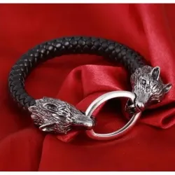 Brazalete de cuero negro con dos cabezas de lobo plateadas en los extremos.