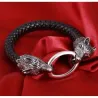 Brazalete de cuero negro con dos cabezas de lobo plateadas en los extremos.